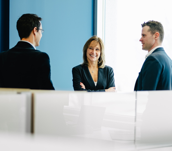 Three people having a conversation in an office setting.
