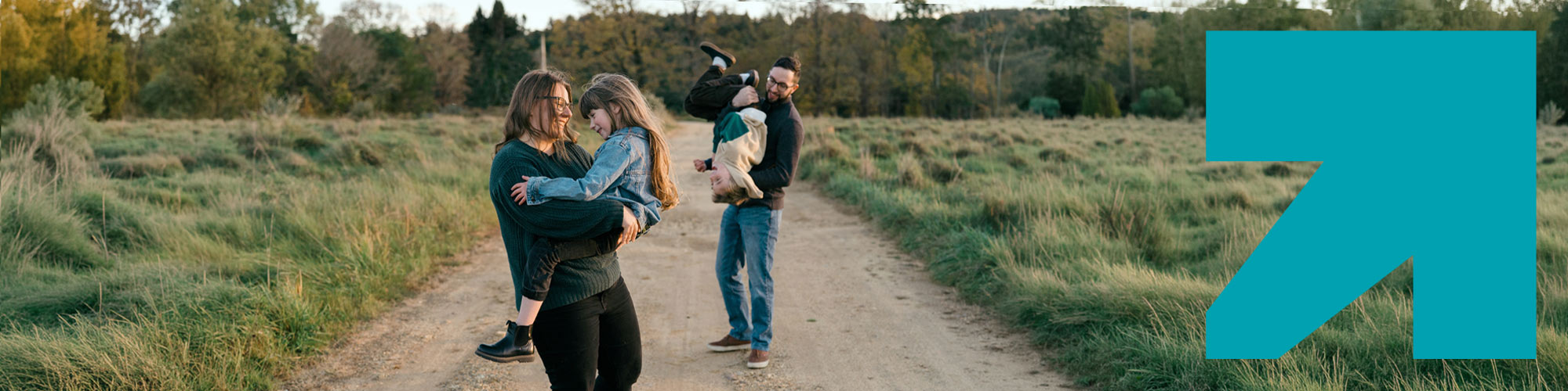 Une famille se promène sur une route dans un champ.
