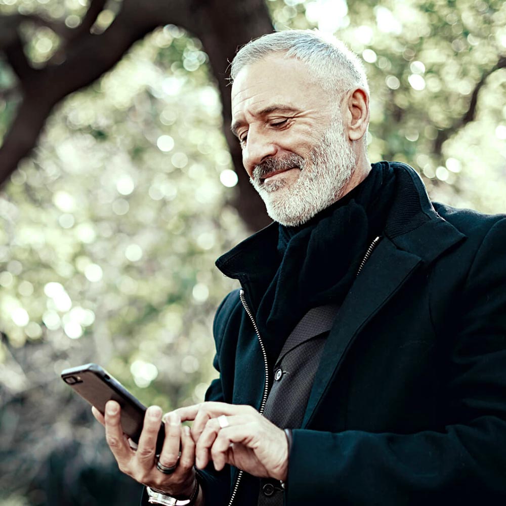 Homme regarde son téléphone cellulaire en souriant