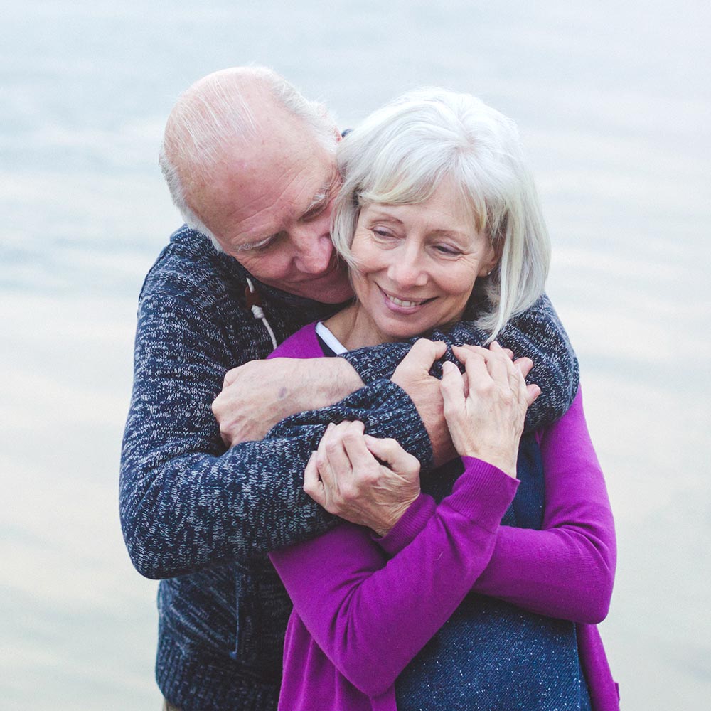 Couple agé s'enlace au bord d'un lac