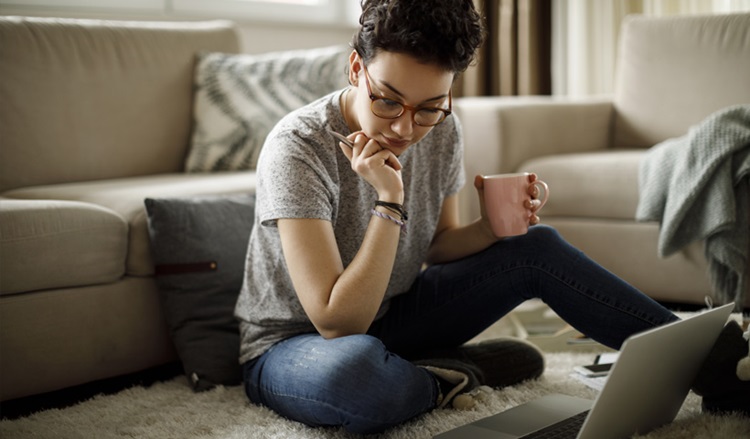 Jeune femme assise dans son salon avec des papiers financiers
