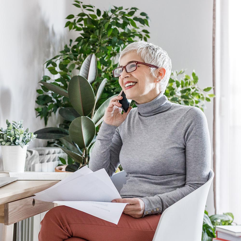 Femme assise parle au téléphone en souriant