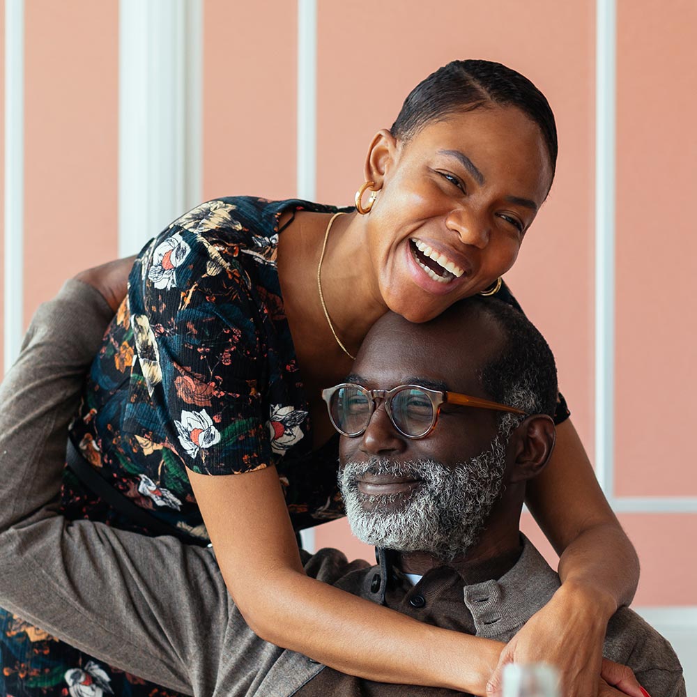 Jeune femme souriante enlace un homme agé