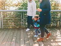 Two parents and one kid walking hand in hand.